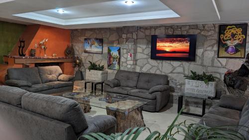 una sala de estar con sofás y una pared de piedra. en Hotel 1988 Guanajuato, en Guanajuato