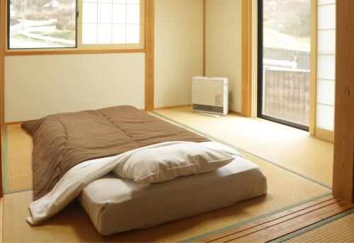 Bett in der Ecke eines Zimmers mit Fenster in der Unterkunft Active House Ryuo - Vacation STAY 04019v in Shimotakai