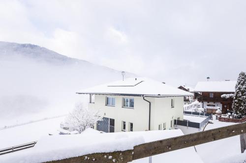 Biały dom z śniegiem na dachu w obiekcie Haus Raich - Pitztal Card im Sommer inklusive w mieście Arzl im Pitztal