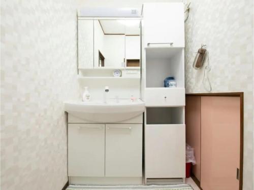 uma casa de banho com um lavatório branco e um espelho. em Minpaku Yamamoto - Vacation STAY 13868 em Izumiotsu