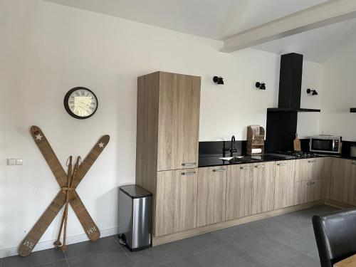 a kitchen with wooden cabinets and a clock on the wall at Gastenverblijf bij de Buuren in Dirksland