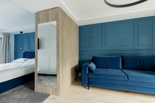 Dormitorio azul con sofá azul y espejo en Aparthotel Nest Inn Meteor en Cluj-Napoca
