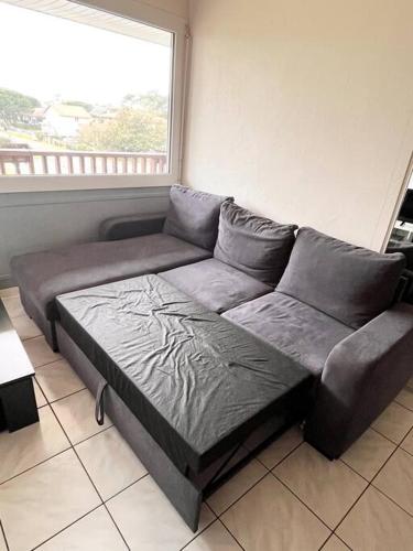 un canapé dans un salon avec une fenêtre dans l'établissement T2 Mimizan plage, à Mimizan