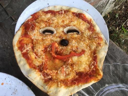 a pizza with a face drawn on top of it at Lovely rural and quiet farmhouse with natural swimming lake in Parsac