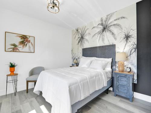 a bedroom with a bed and a chair and palm trees on the wall at Rainbow Motel Miami in Miami