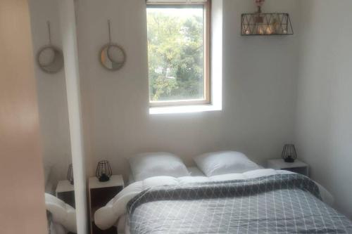 un lit dans une chambre blanche avec une fenêtre dans l'établissement à 7 min de Paris, 2 pièces 