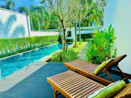 a wooden bench sitting next to a swimming pool at White Lotus by Oxygen at Bang Tao Beach in Ban Thalat Choeng Thale