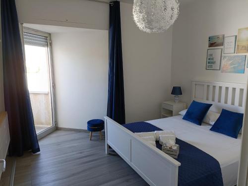 Un dormitorio con una cama con almohadas azules y una ventana. en Villa Marthan, en San Vito lo Capo