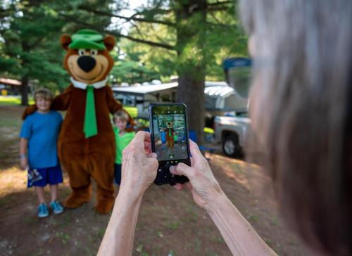 a person taking a picture of a person dressed in a bear costume at Yogi Bear's Jellystone Park Camp-Resort Wisconsin Dells in Wisconsin Dells