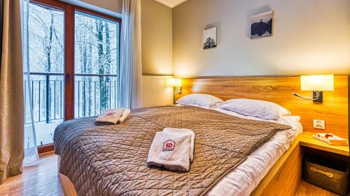 a bedroom with a large bed with two towels on it at Apartament 28 z Basenem i SPA - 5D Apartments in Szklarska Poręba