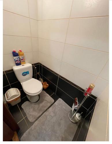 a bathroom with a white toilet and black tiles at The12 отдельная комната in Bishkek