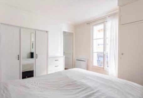 a white bedroom with a white bed and a window at SUITE ELISE Passy in Paris