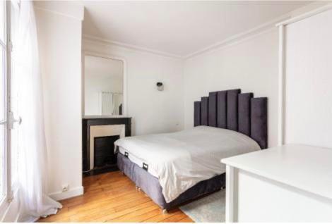 Habitación blanca con cama y espejo en SUITE ELISE Passy, en París