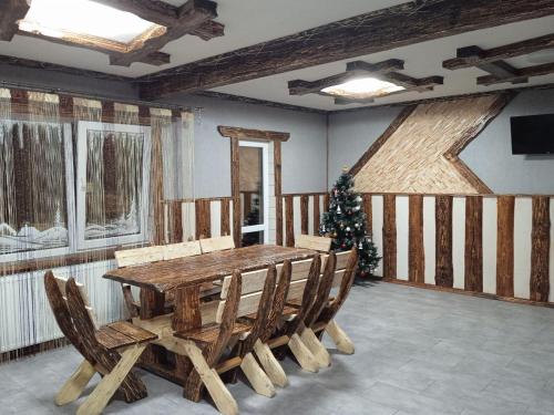 a dining room with a wooden table and a christmas tree at Кольорові подорожі 2 in Slavske