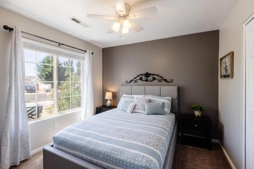 a bedroom with a bed with a ceiling fan and a window at 310 La Verkin Private Hot Tub, Spacious yard, near Zion National Park and St George in La Verkin