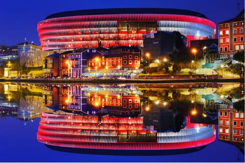 a building with red and white lights next to a body of water at Apartamento Portugalete Gran Bilbao 3 dormitorios - 3 bedrooms in Portugalete