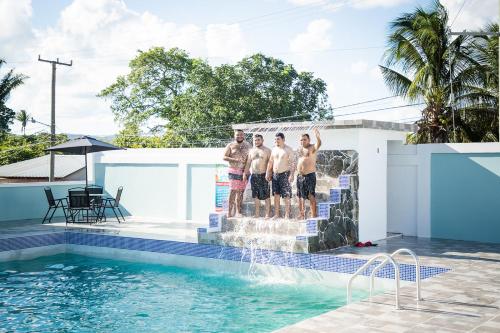 un grupo de hombres parados en el borde de una piscina en La Cascada Stays en San Ignacio
