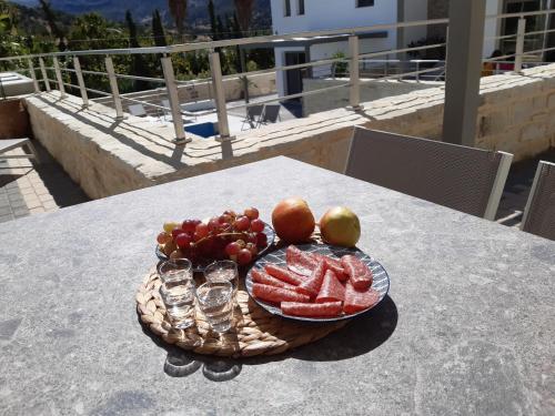 a plate of fruit on a table with glasses at Matala Prime Villas in Matala