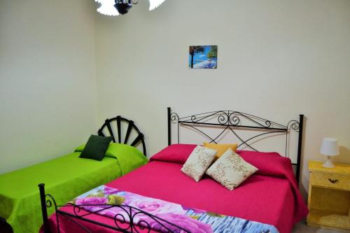 トッレ・ラピッロにあるSea Apartmentのベッドルーム1室(緑とピンクのシーツが備わるベッド2台付)