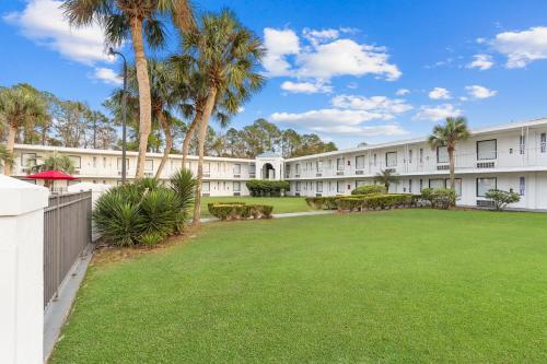 a large yard in front of a building with palm trees at Baymont by Wyndham Jacksonville Airport in Jacksonville