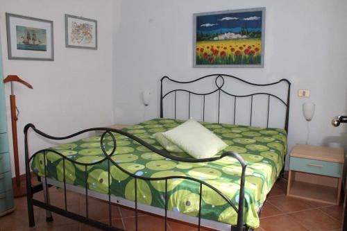 ein Schlafzimmer mit einem Bett mit einer grünen Bettdecke in der Unterkunft Villetta Trilocale con Giardino 1.3 in Porto Pollo