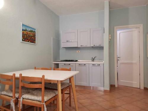 eine Küche mit einem Tisch und Stühlen sowie weißen Schränken in der Unterkunft Villetta Trilocale con Giardino 1.3 in Porto Pollo