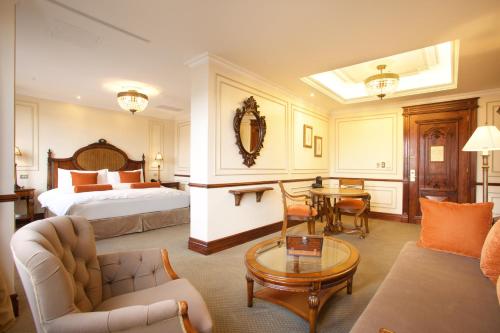 um quarto de hotel com uma cama, um sofá e uma mesa em Plaza Grande Hotel em Quito