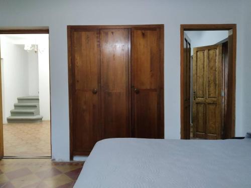 1 dormitorio con 1 cama y 2 puertas de madera en Finca La Codiciada en San Rafael