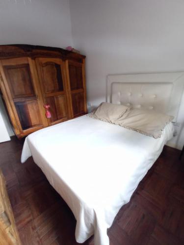 Cama blanca en habitación con armario de madera en Mari mari en Gualeguaychú