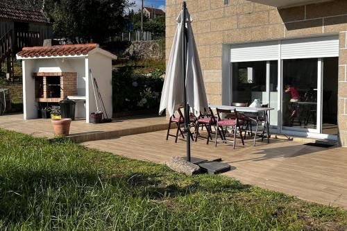 patio con ombrellone, tavolo e sedie di Agradable casa rural entre Pontevedra y Arcade a Pontevedra