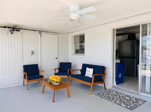 um alpendre com 3 cadeiras, uma mesa e uma ventoinha de tecto em Cheerful home with two Bedrooms em Cape Coral