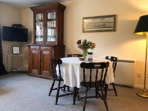 una mesa de comedor con un jarrón de flores. en Manyleith Rig Cottage en Polmood