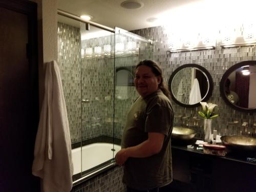Holiday Inn Desert Club Resort في لاس فيغاس: رجل واقف امام شطاف بالحمام