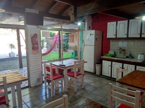 een keuken met een tafel, stoelen en een koelkast bij Merlo Hostel in Merlo