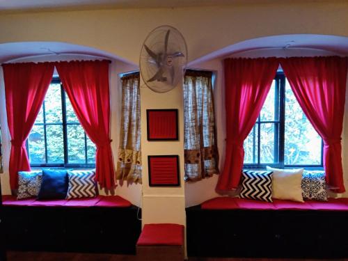 twee bedden in een kamer met rode gordijnen en ramen bij Merlo Hostel in Merlo