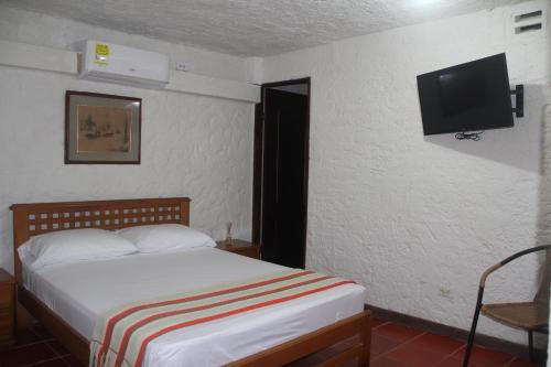 um quarto com uma cama e uma televisão de ecrã plano em Villa Margarita em Puerto Colombia