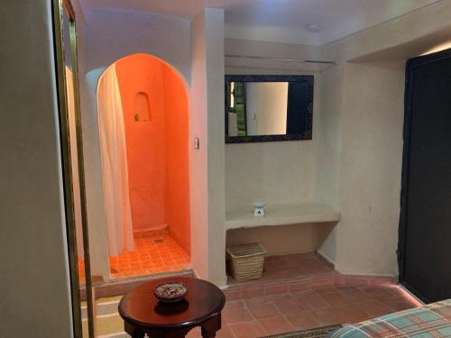 La salle de bains est pourvue d'une douche orange et d'une table. dans l'établissement Auberge Ayam Atlas, à Ourika