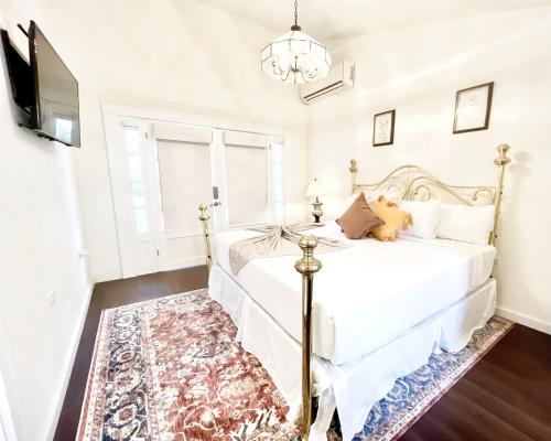 a white bedroom with a bed and a tv at La Villa de Adelina in Ensenada