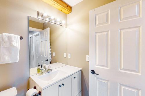 Un baño con un lavabo blanco y un espejo. en Snow Pines & Ice and Cozy, en Big White