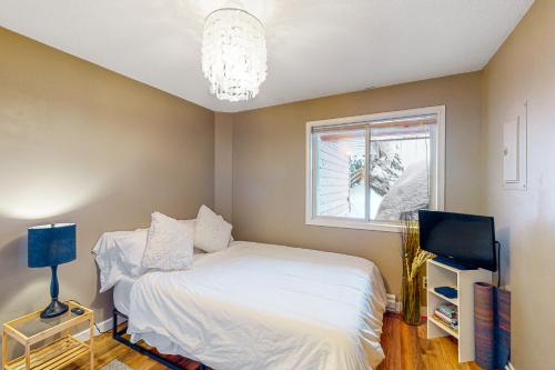 a bedroom with a white bed and a window at Snow Pines & Ice and Cozy in Big White