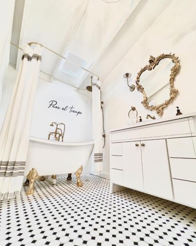 a bathroom with a white tub and a black and white tiled floor at La Villa de Adelina in Ensenada