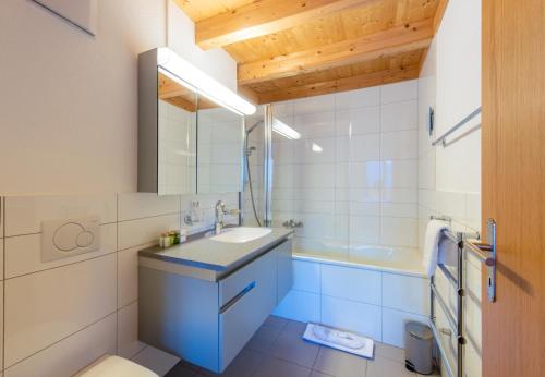 łazienka z umywalką, toaletą i wanną w obiekcie Racers Retreat 10 w mieście Wengen