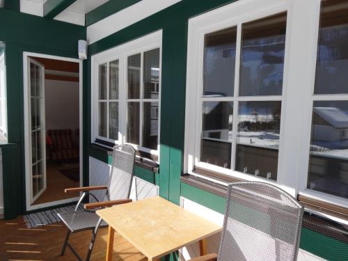 a table and chairs on a balcony with windows at Apartmenthaus Edelweiss in Gosau in Gosau