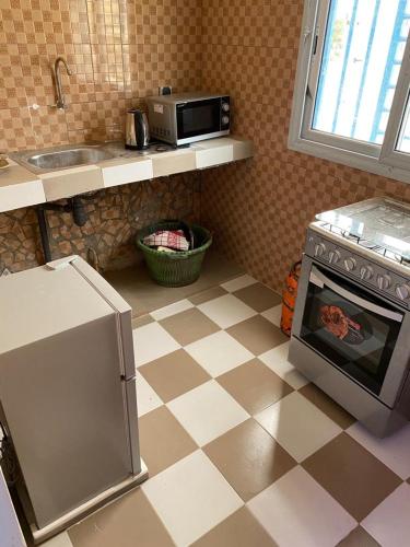 a kitchen with a tiled floor with a stove and a microwave at Studio meublé 1 à ouakam Comico Dakar in Dakar