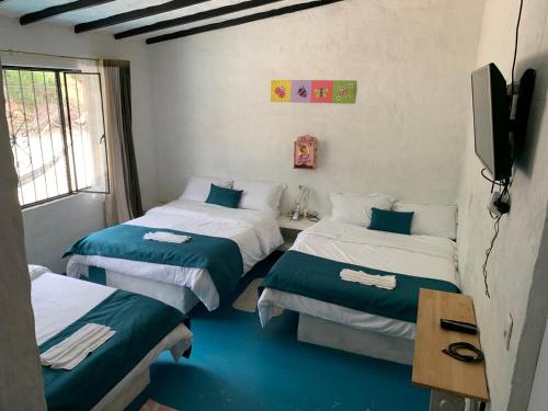 a room with two beds and a television in it at FINCA VILLA PEDREGAL RAQUIRA in Ráquira