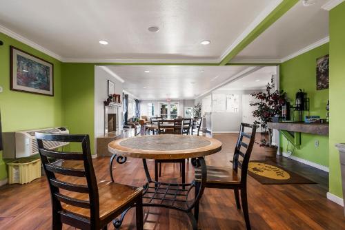 a dining room with green walls and a table and chairs at Heritage Inn Express Chico in Chico