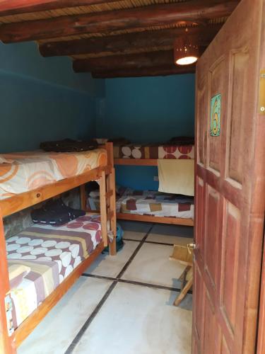 a room with three bunk beds and a door at Tilcara Rustica Hostel in Tilcara