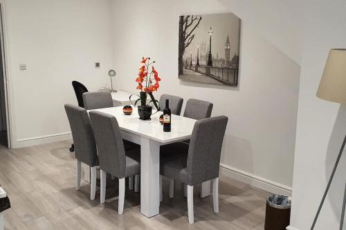 a white dining room table with chairs and a vase of flowers at Daisy Lodge - Spacious Two Bed Flat - Parking, Netflix, WIFI - Close to Blenheim Palace & Oxford - F1 in Kidlington
