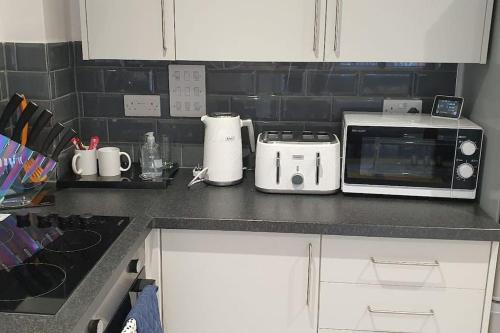 a kitchen counter with a toaster and a microwave at Daisy Lodge - Spacious Two Bed Flat - Parking, Netflix, WIFI - Close to Blenheim Palace & Oxford - F1 in Kidlington