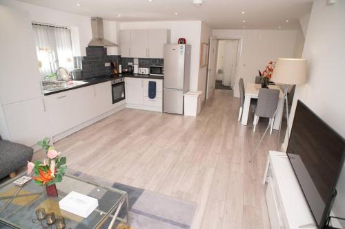 a kitchen and living room with a table and a refrigerator at Daisy Lodge - Spacious Two Bed Flat - Parking, Netflix, WIFI - Close to Blenheim Palace & Oxford - F1 in Kidlington